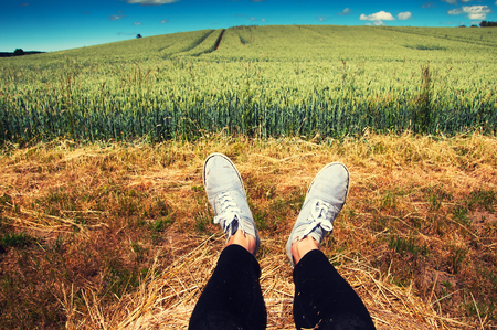 Woman's legs with blue shoes sitting on a baleの写真素材