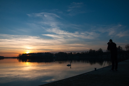 Silhouette of a man photographing sunset from a jettyの写真素材
