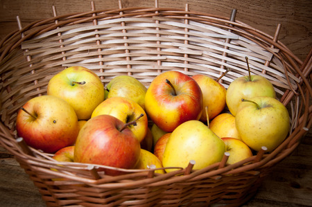Apples sitting in a wooden basket on wooden backgroundの写真素材