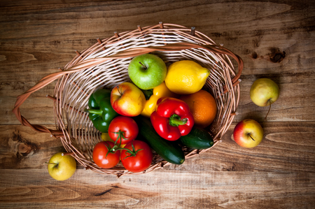 Basket with vegetables and fruits on wooden backgroundの写真素材