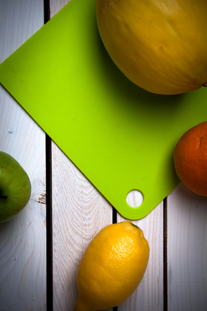Fruits on green cutting board, white tableの写真素材