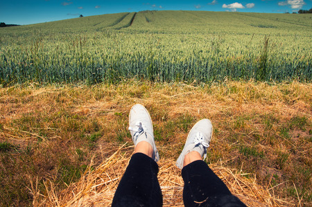 Woman's legs with blue shoes sitting on a baleの写真素材