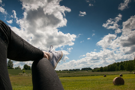 Woman's legs with blue shoes sitting on a baleの写真素材