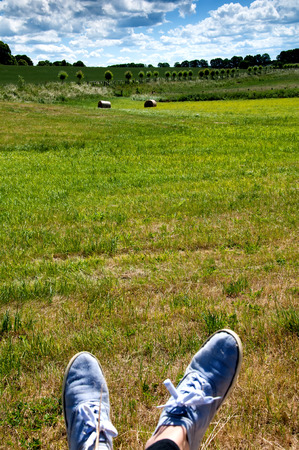 Woman's legs with blue shoes sitting on a baleの写真素材