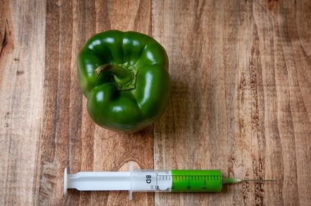 GMO green pepper and syringe on wooden backgroundの写真素材