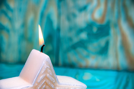 Christmas star shaped candle on blue backgroundの写真素材