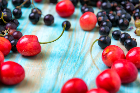 Black currant and cherries on blue wooden backgroundの写真素材