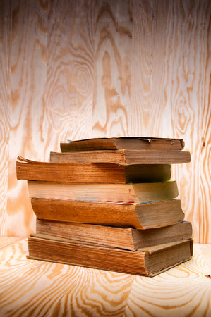 Vintage antiquarian books pile on wooden surfaceの写真素材