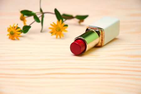 Red lipstick and flower on wooden backgroundの写真素材