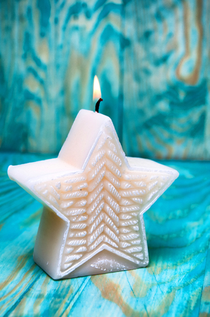 Christmas star shaped candle on blue backgroundの写真素材