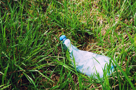 Crushed plastic bottle of mineral water on grassの写真素材