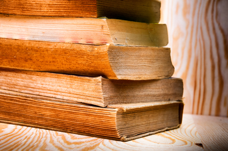 Vintage antiquarian books pile on wooden surfaceの写真素材