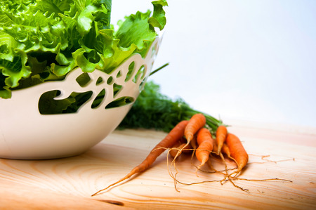 Carrots and salad on wooden tableの写真素材