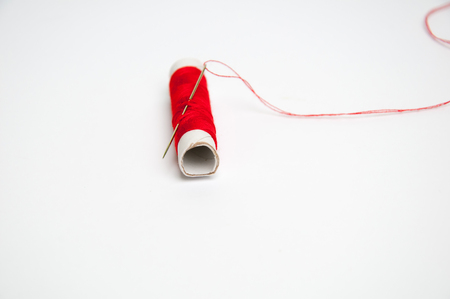 Red sewing thread and needle isolated on white backgroundの写真素材