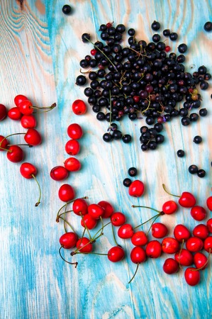 Black currant and cherries on blue wooden backgroundの写真素材