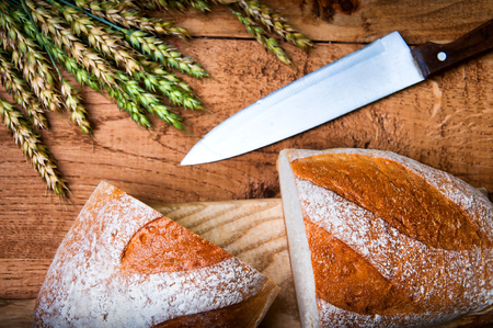 Fresh bread, wheat and knife on wooden backgroundの写真素材