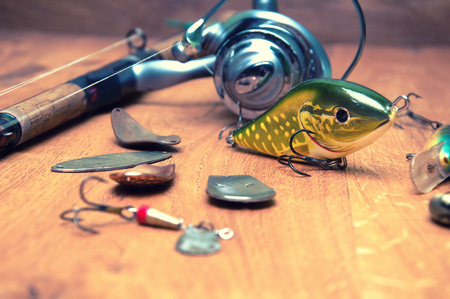 Fishing baits and rod isolated on wooden backgroundの写真素材