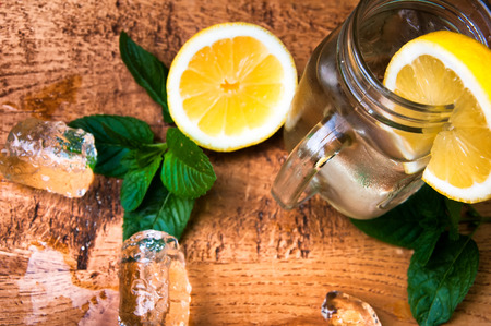 Cold fresh lemonade drink and ice cubes on wooden backgroundの写真素材