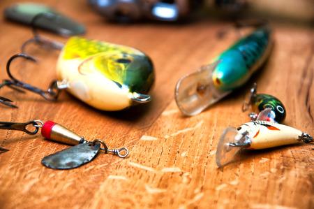 Fishing baits and rod isolated on wooden backgroundの写真素材