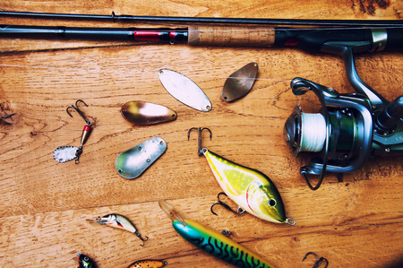 Fishing baits and rod isolated on wooden backgroundの写真素材