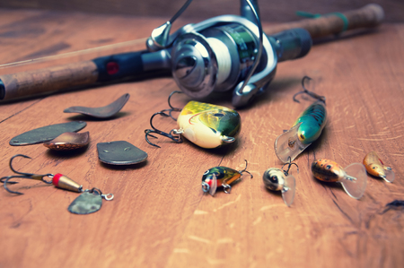 Fishing baits and rod isolated on wooden backgroundの写真素材