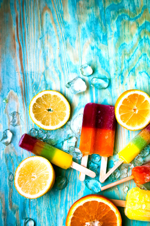 Colorful ice lolly and friuts on blue wooden backgroundの写真素材