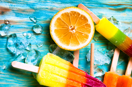 Colorful ice lolly and friuts on blue wooden backgroundの写真素材
