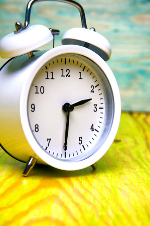 White alarm clock isolated on colorful wooden backgroundの写真素材