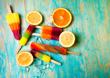 Colorful ice lolly and friuts on blue wooden backgroundの写真素材