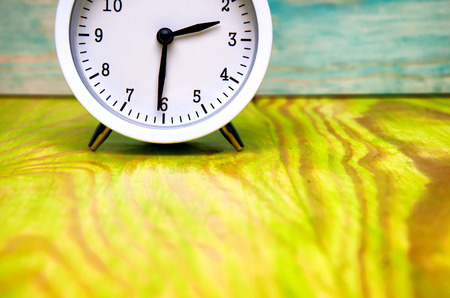 White alarm clock isolated on colorful wooden background