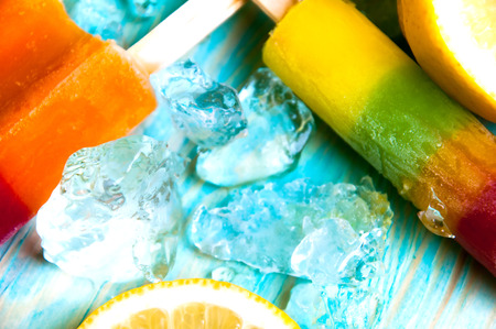 Colorful ice lolly and friuts on blue wooden backgroundの写真素材