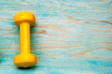 Yellow dumbbell 1kg on blue wooden backgroundの写真素材