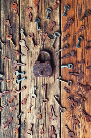 Old rusty padlock and keys on wooden backgroundの写真素材
