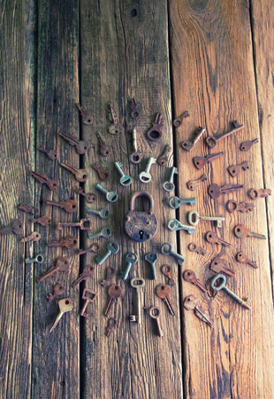Old rusty padlock and keys on wooden backgroundの写真素材