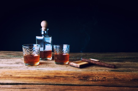 Whisky with ice and cigar on wooden tableの写真素材