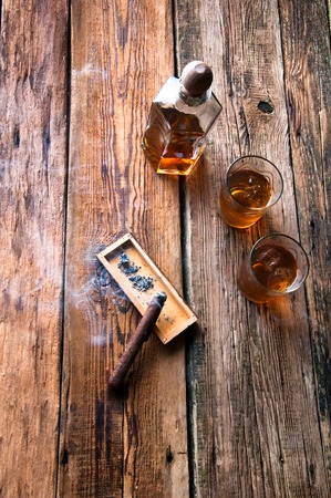 Whisky with ice and cigar on wooden tableの写真素材