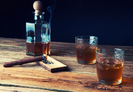 Whisky with ice and cigar on wooden tableの写真素材