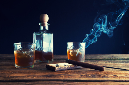 Whisky with ice and cigar on wooden tableの写真素材
