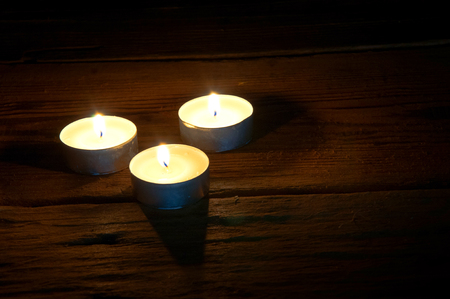 Burning tealights on dark wooden background. Copyspaceの写真素材