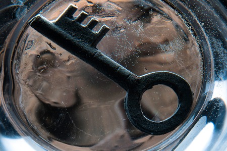 Old rusty key on the bottom of glass of waterの写真素材