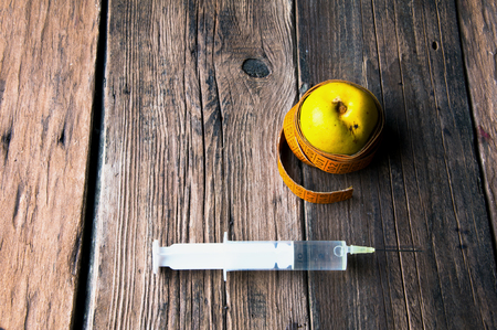 Green apple wrapped with tape measure and a syringeの写真素材