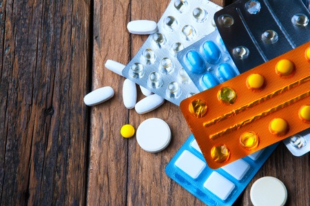 Many pills - medications and supplements. Wooden background. Copyspace