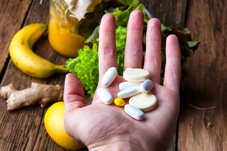 Choice between vitamins from supplements or from vegetables and fruitsの写真素材