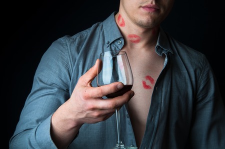 Drunk man with many lipstick stamps drinking wineの写真素材