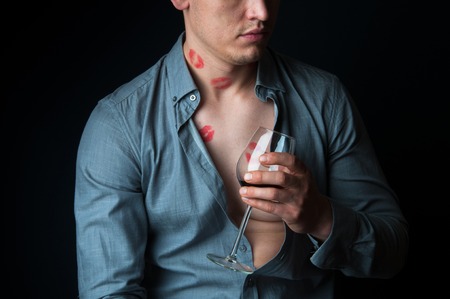 Drunk man with many lipstick stamps drinking wineの写真素材