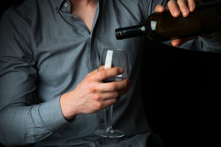 Drunk man with lipstick stamps pouring wine into glassの写真素材