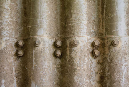Texture of old weathered corrugated iron. With screws and nuts. You can see the age on the surface.