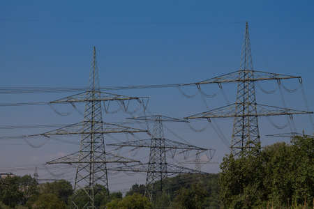 A route with many high-voltage pylons and accordingly many lines, which is led through a forest.の写真素材