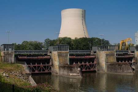 Three locks of a hydropower plant with a machine house. And a cooling tower of a nuclear power plant in the background.の写真素材