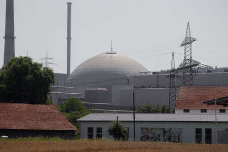 In the middle of the reactor dome and on the left behind the machine house with the steam turbines of a nuclear power plant and in the foreground some administration buildings.の写真素材